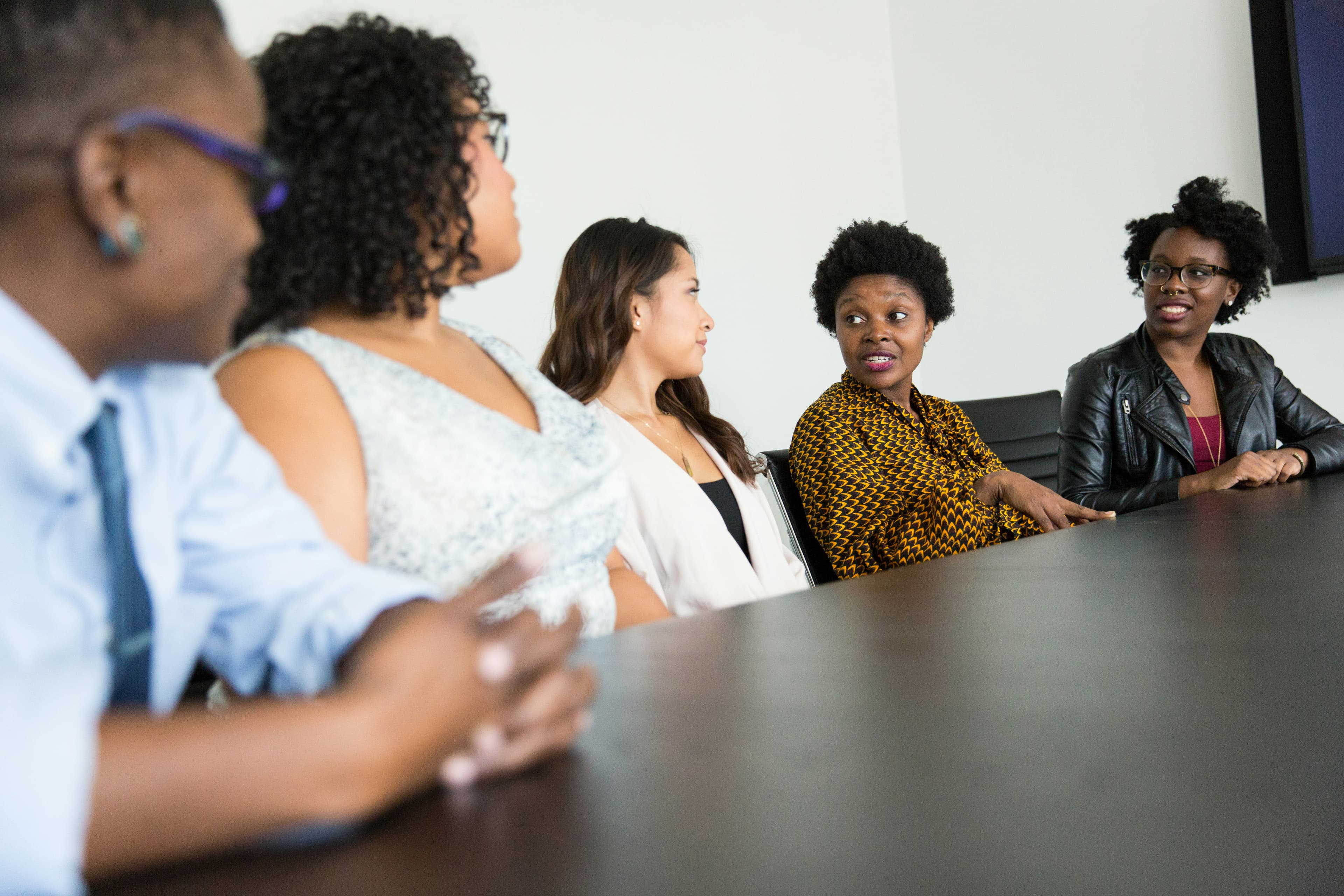 Grupo diverso de colegas reunidos em uma mesa de trabalho, conversando